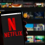 Dłoń trzyma smartfon z logo Netflix. Zastanawiasz się, ile kosztuje Netflix?