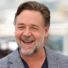 Uśmiechnięty Russell Crowe w szarym garniturze. Zastanawiasz się, ile lat ma Russell Crowe?