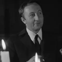 Bogumił Kobiela w jednym z filmów, w eleganckim garniturze, przy blasku świec.