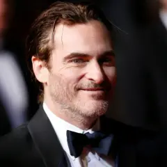 Joaquin Phoenix, który grał Jokera w filmie Joker, w czarnym smokingu i muszce.
