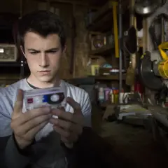 Clay Jensen z serialu "13 powodów" trzyma kasetę z nagraniem w warsztacie pełnym narzędzi.