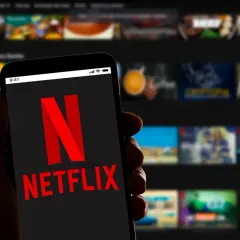 Dłoń trzyma smartfon z logo Netflix. Zastanawiasz się, ile kosztuje Netflix?