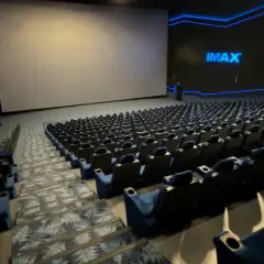 Pusta sala kinowa IMAX z ogromnym ekranem i rzędami niebieskich foteli. To właśnie co to znaczy IMAX w kinie – niesamowite wrażenia wizualne.