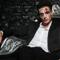 Mężczyzna w garniturze, z krwią na twarzy, siedzi na ozdobnym tronie. Czy Patrick Bateman naprawdę zabijał?