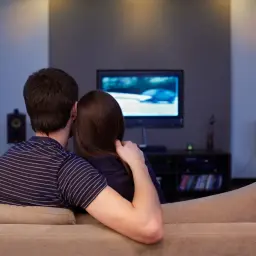 Para spędza wieczór na kanapie, oglądając film. To właśnie oznacza "netflix and chill" – wspólne relaksowanie się przy dobrym serialu lub filmie.
