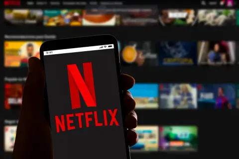 Dłoń trzyma smartfon z logo Netflix. Zastanawiasz się, ile kosztuje Netflix?
