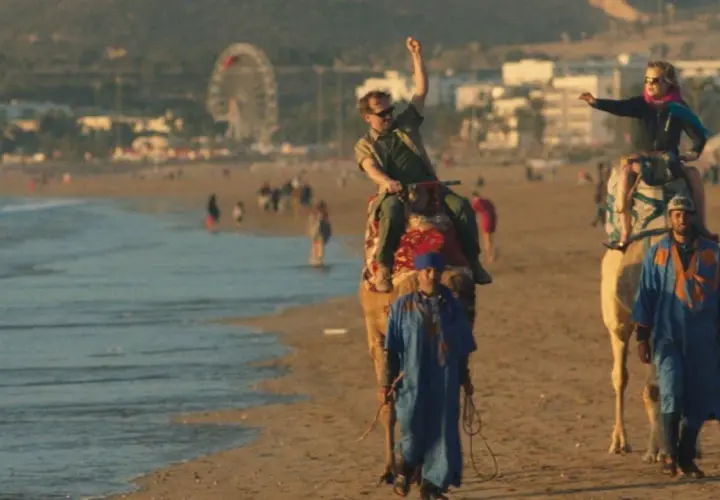 Wycieczka na wielbłądach po plaży, jak z filmu all inclusive. W tle wesołe miasteczko i tłum ludzi.