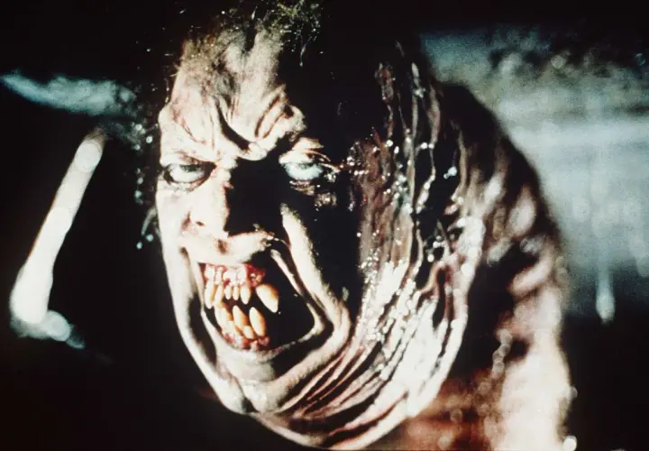 Przerażająca twarz potwora z zębami jak sztylety, w stylu found footage horror.