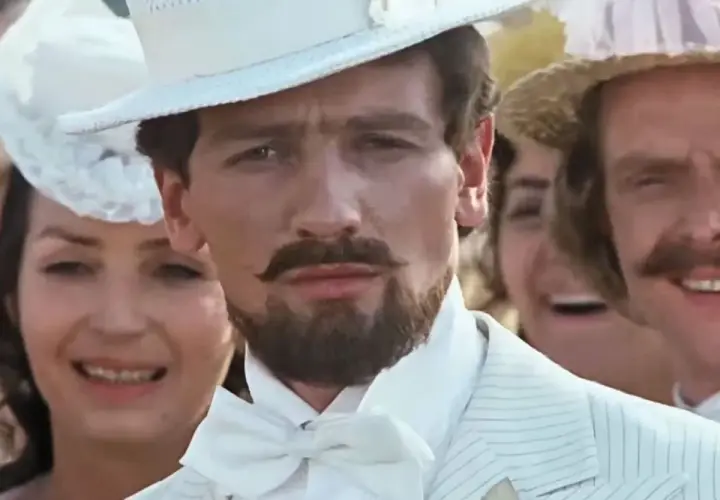 Mężczyzna w białym cylindrze i garniturze, jak z filmu "Noce i dnie", z wąsami i bródką.