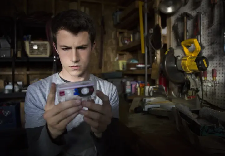 Clay Jensen z serialu "13 powodów" trzyma kasetę z nagraniem w warsztacie pełnym narzędzi.