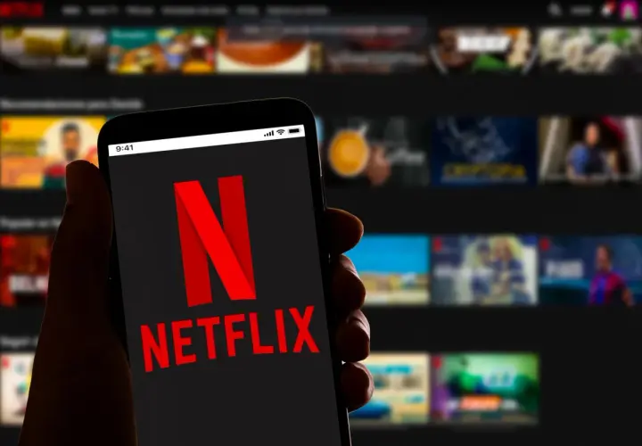 Dłoń trzyma smartfon z logo Netflix. Zastanawiasz się, ile kosztuje Netflix?