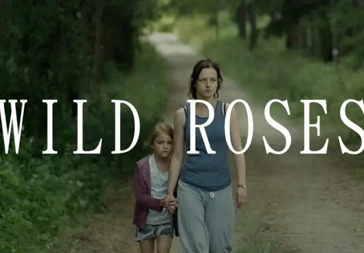 Kobieta i dziewczynka idą ścieżką w lesie. Napis "WILD ROSES" sugeruje, że to kadr z filmu.