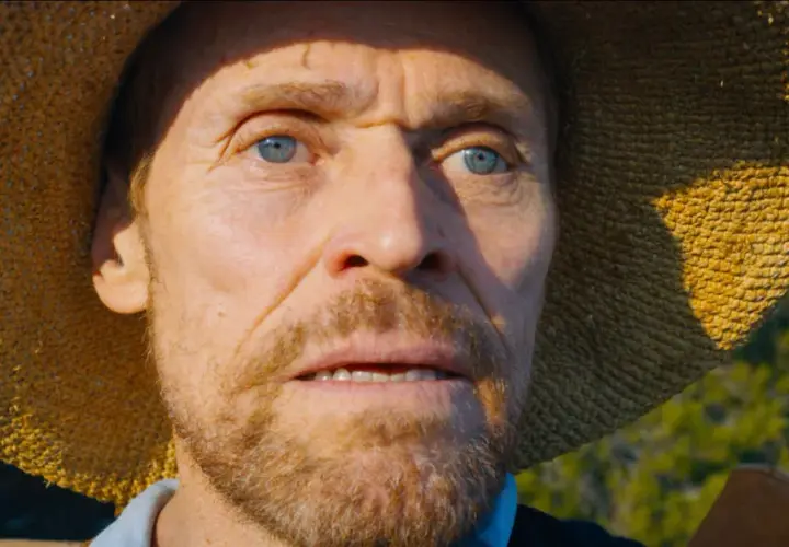 Willem Dafoe jako Van Gogh u Bram Wieczności, z niebieskimi oczami i słomkowym kapeluszem, wpatruje się w dal.