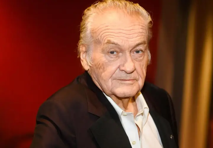 Jerzy Skolimowski, reżyser znany z wyrazistych filmów, na tle czerwonej kurtyny.