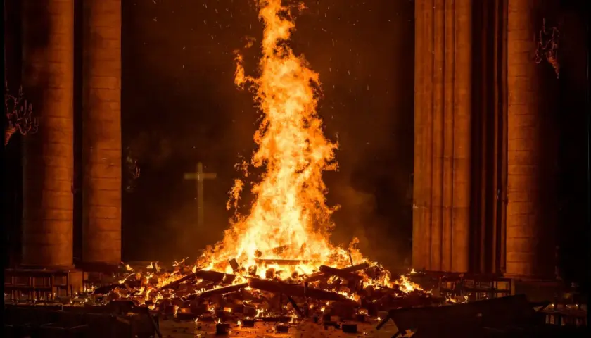Płomienie ognia unoszą się wysoko, gdy notre-dame płonie. W tle widać krzyż.