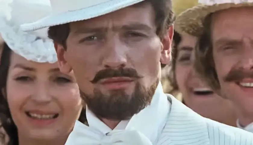 Mężczyzna w białym cylindrze i garniturze, jak z filmu "Noce i dnie", z wąsami i bródką.