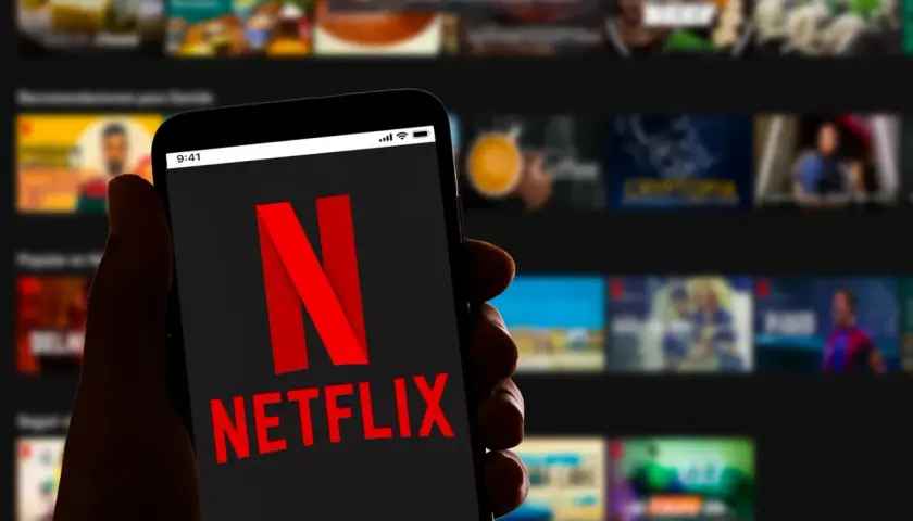 Dłoń trzyma smartfon z logo Netflix. Zastanawiasz się, ile kosztuje Netflix?