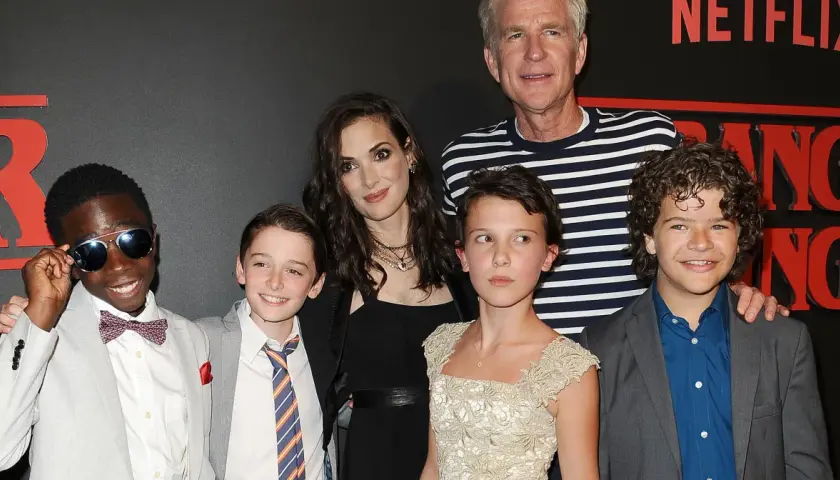 Aktorzy z "Stranger Things" pozują do zdjęcia. Millie Bobby Brown, która gra Eleven, wygląda na około 16 lat, co sugeruje, że w 4. sezonie mogła mieć podobny wiek.