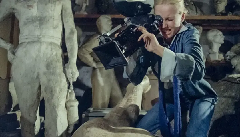 Kobieta z kamerą w pracowni rzeźbiarskiej, jak z filmów Feliksa Falka. W tle antyczne posągi.