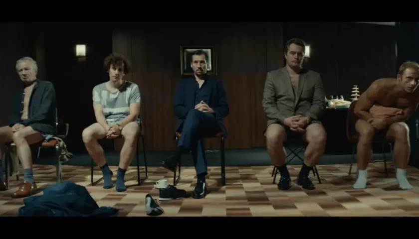 Pięciu mężczyzn siedzi na krzesłach, każdy w innym stroju. Scena z filmu "samiec alfa".
