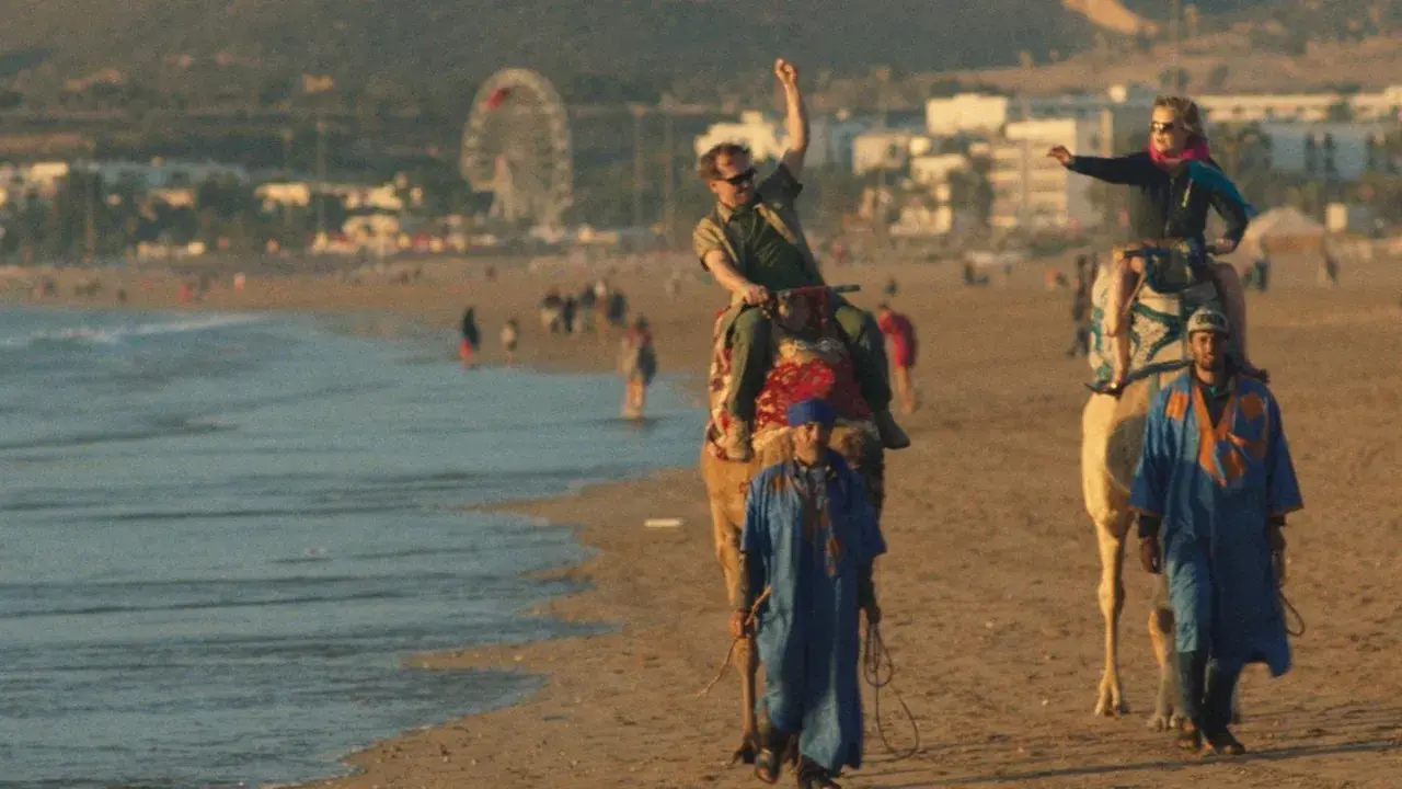 Wycieczka na wielbłądach po plaży, jak z filmu all inclusive. W tle wesołe miasteczko i tłum ludzi.