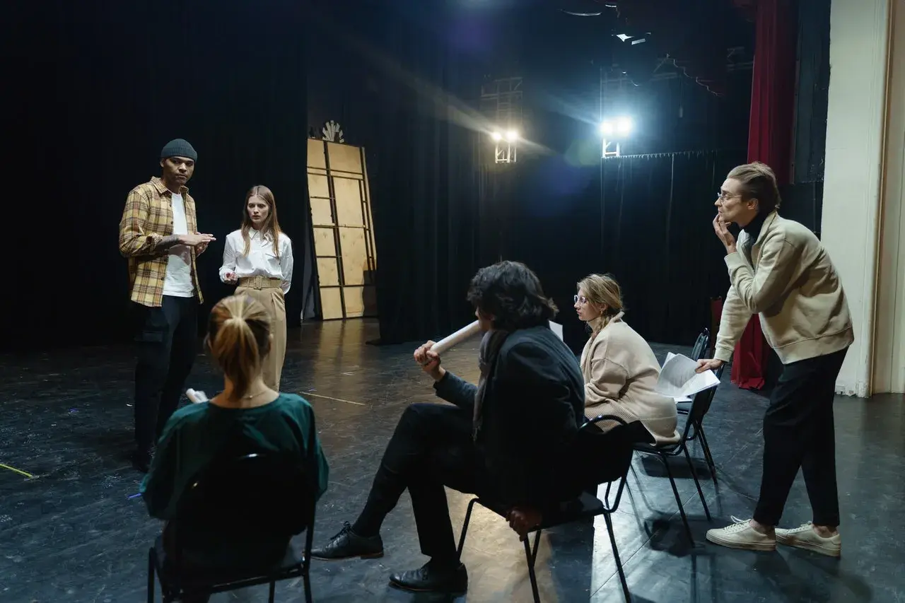Aktorzy na próbie dyskutują o tym, ile zarabiają aktorzy w teatrze, analizując scenariusz.
