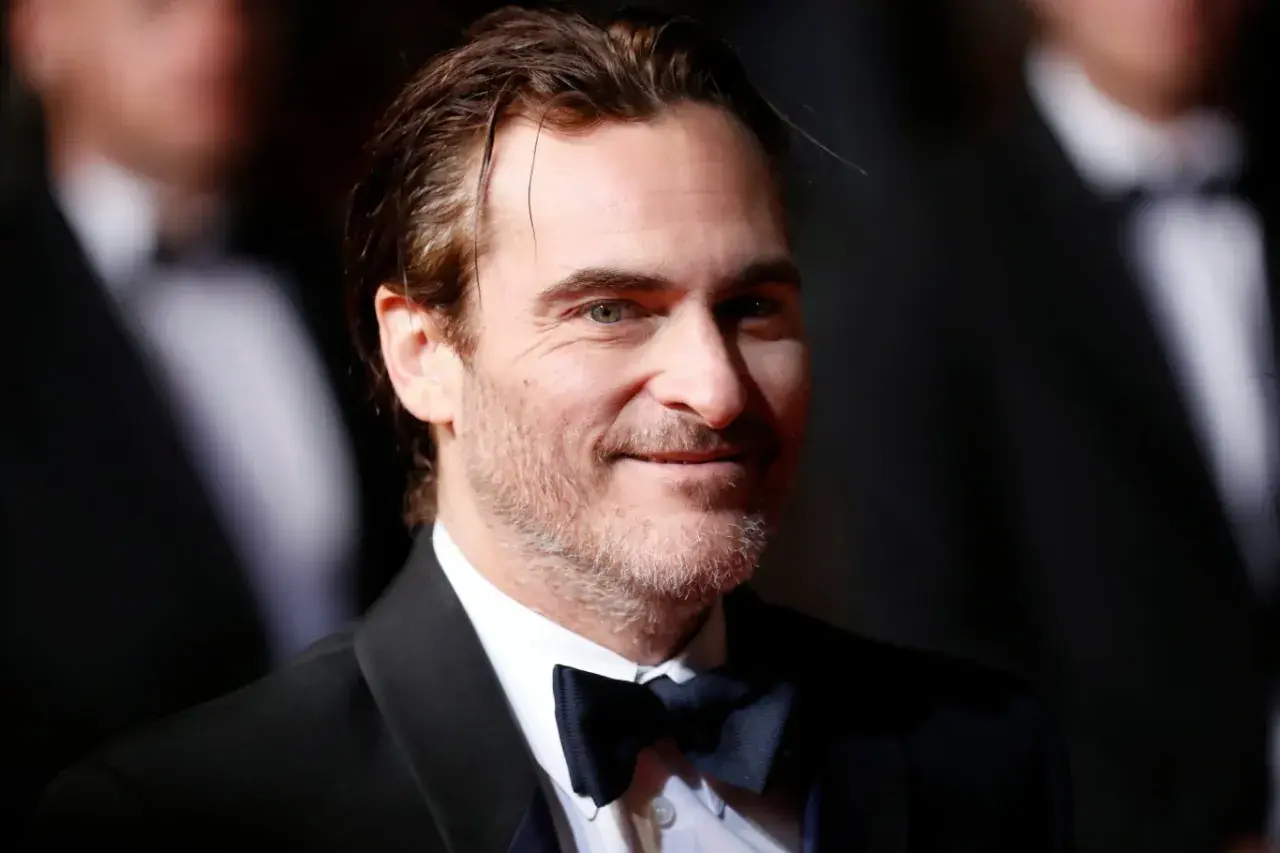 Joaquin Phoenix, który grał Jokera w filmie Joker, w czarnym smokingu i muszce.