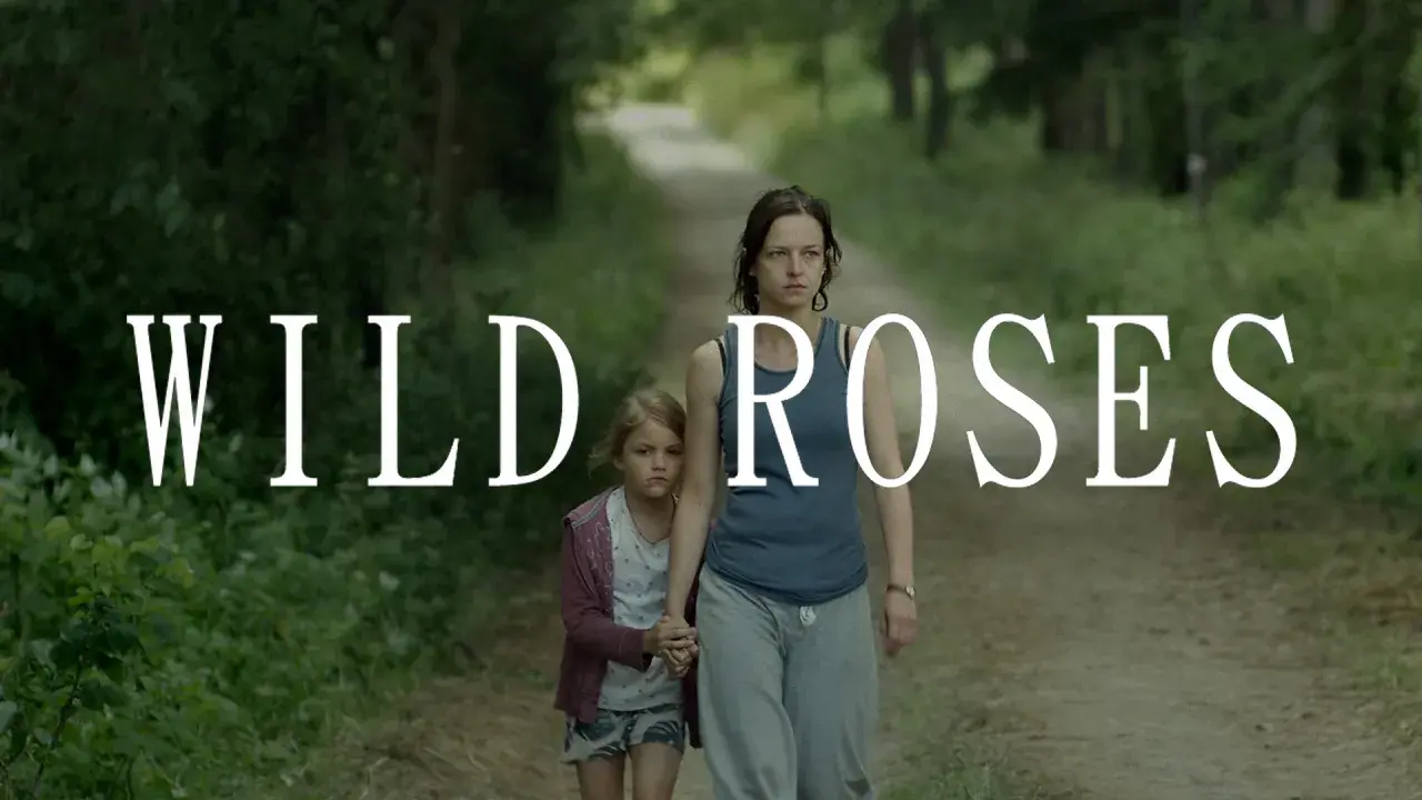 Kobieta i dziewczynka idą ścieżką w lesie. Napis "WILD ROSES" sugeruje, że to kadr z filmu.