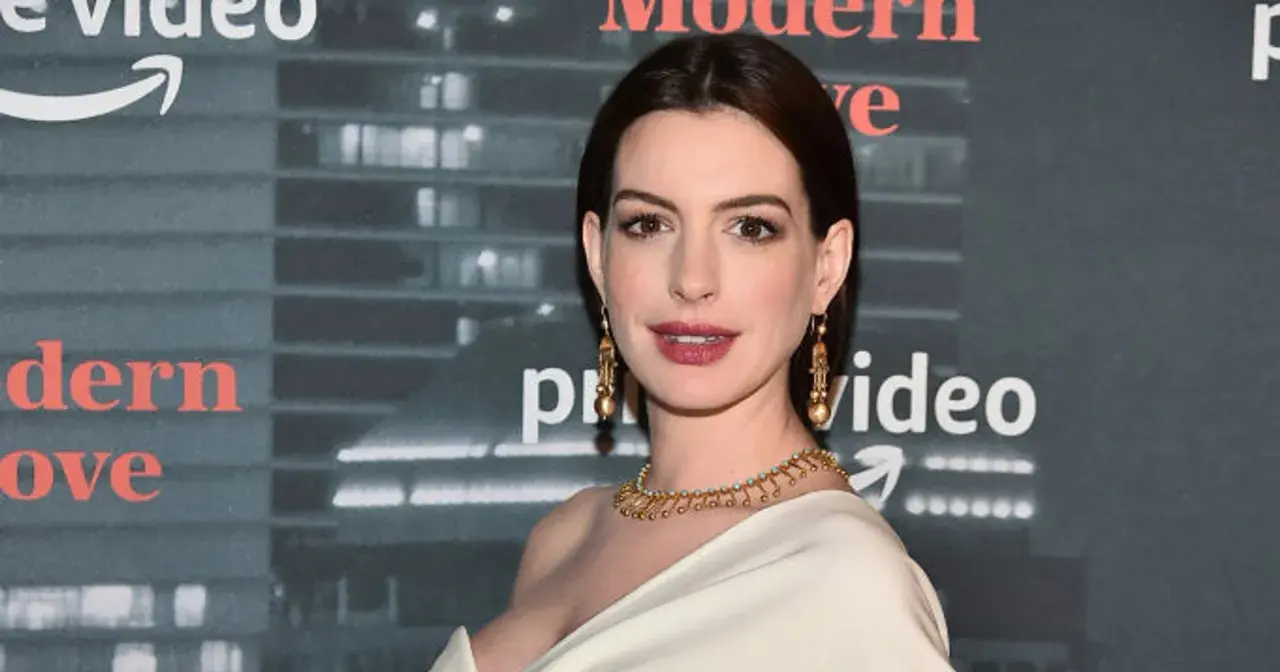Anne Hathaway, której wiek jest często przedmiotem dyskusji, prezentuje się olśniewająco w złotej biżuterii na tle logo Amazon Prime Video.