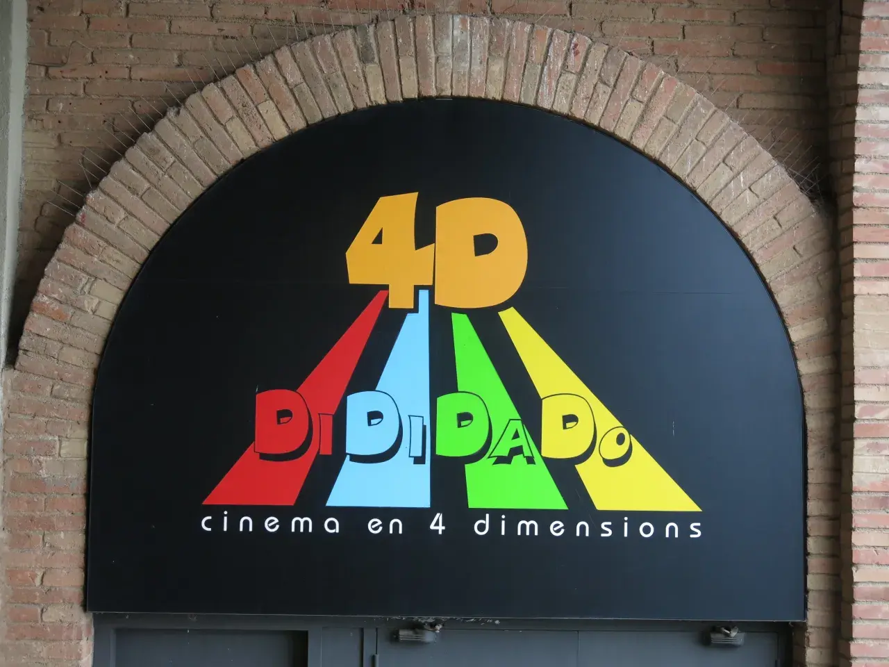 Logo "DIDIDADO" z napisem "cinema en 4 dimensions" pod łukiem z cegły. To właśnie co to jest 4DX – kino z dodatkowymi doznaniami.