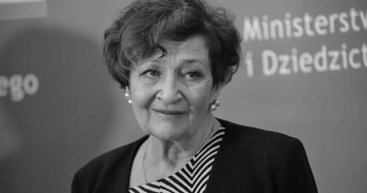 Uśmiechnięta Ewa Dałkowska, aktorka znana z wielu filmów, w eleganckiej stylizacji.
