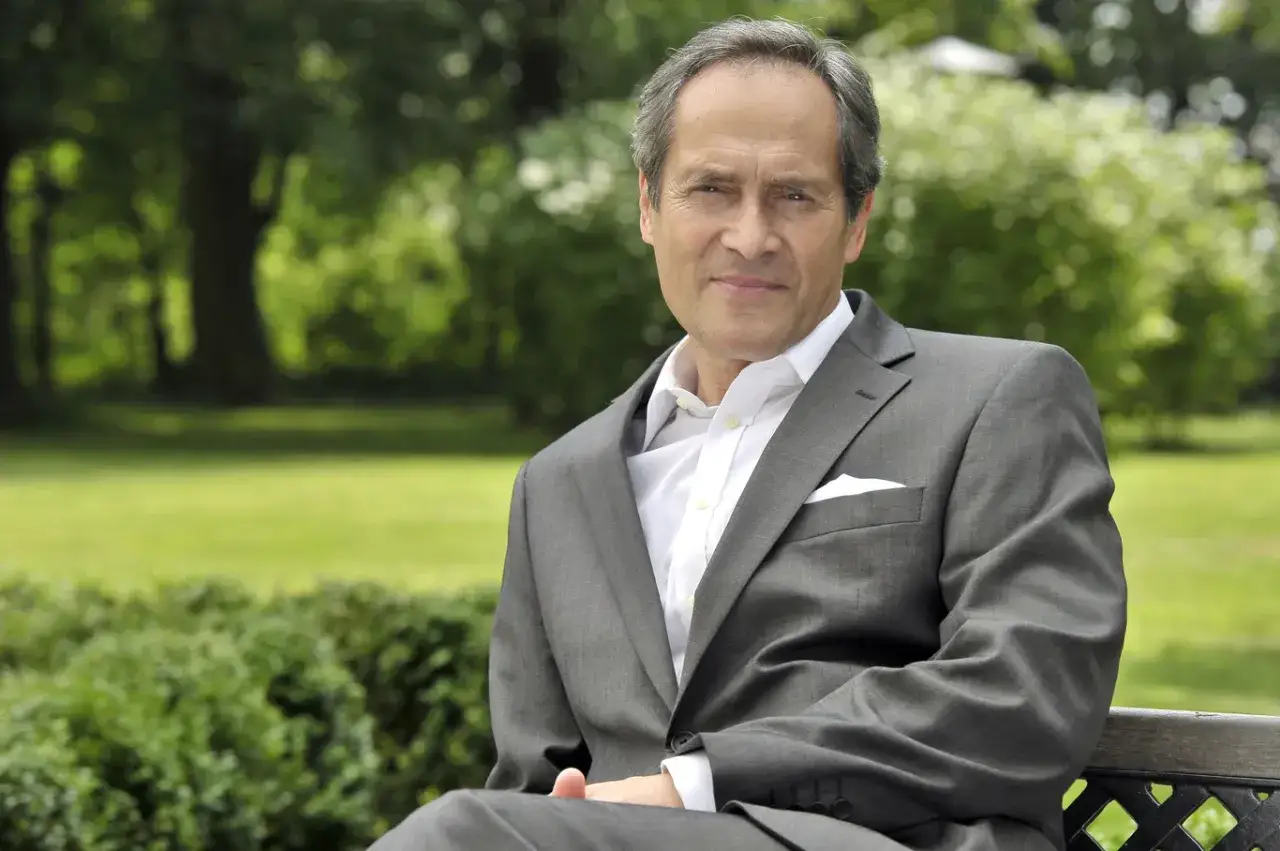 Jerzy Zelnik w eleganckim garniturze, siedzący na ławce w parku. Jego charakterystyczna twarz znana z wielu polskich filmów.
