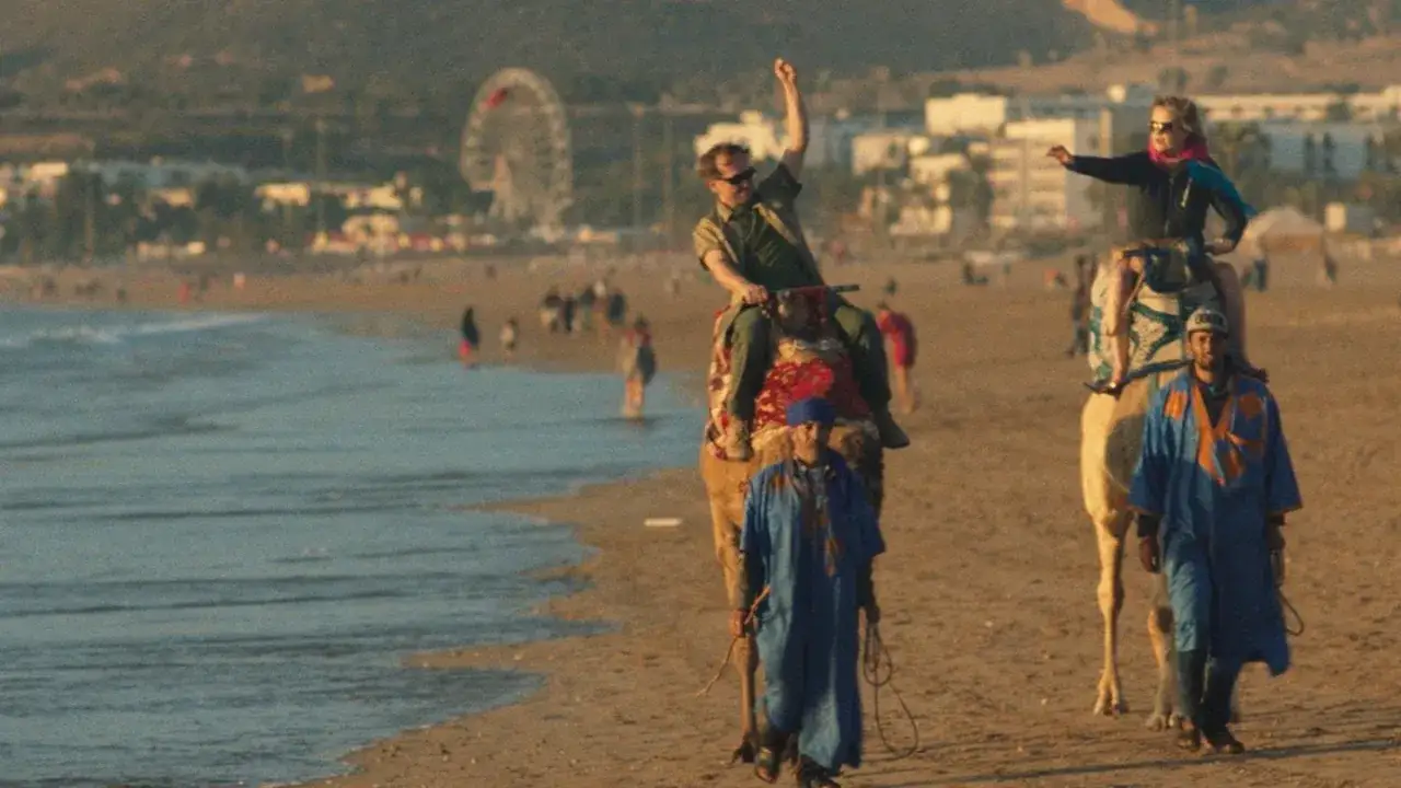 Wycieczka wielbłądami na plaży, jak z filmu all inclusive. W tle wesołe miasteczko.
