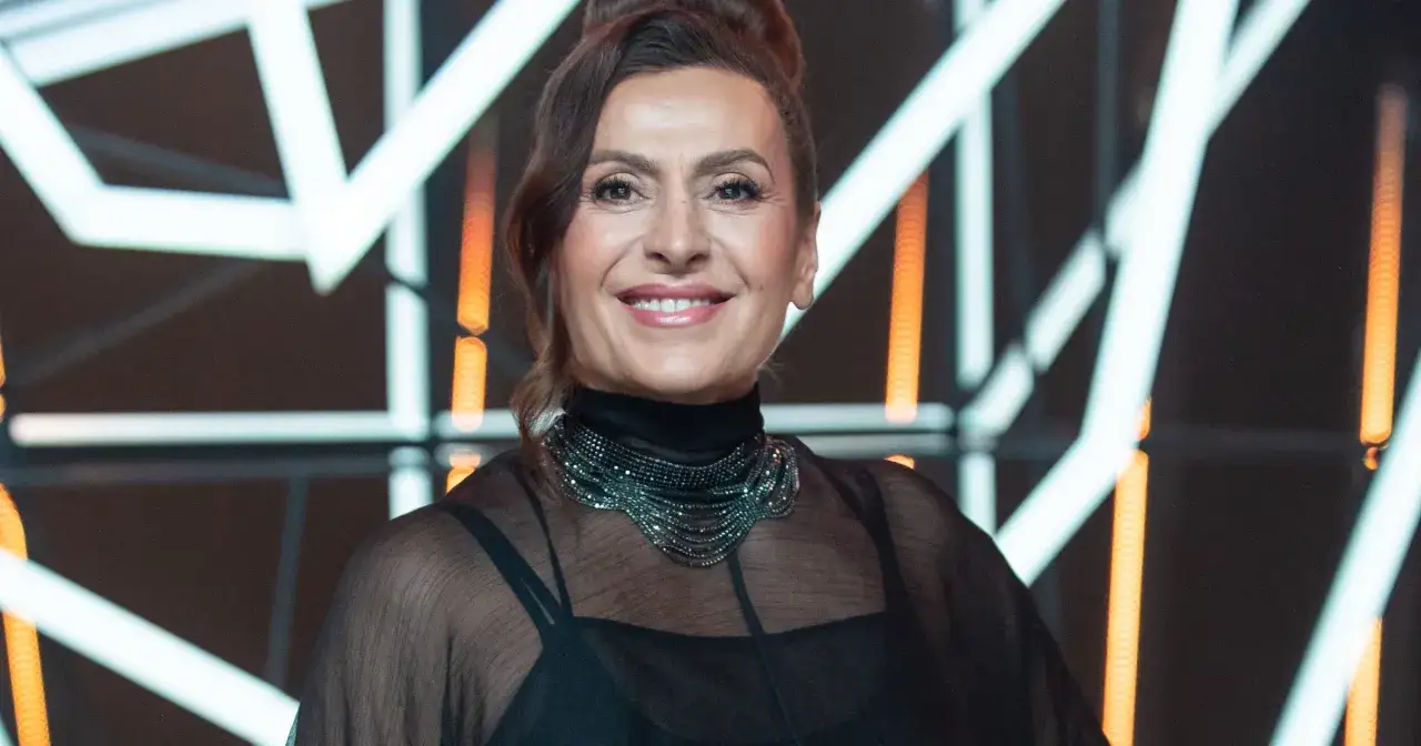 Uśmiechnięta kobieta w czarnej, prześwitującej bluzce z ozdobnym naszyjnikiem. Czyżby to Violetta Capsa?