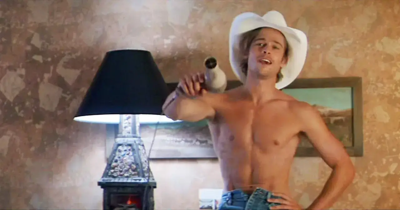 Brad Pitt w białym kapeluszu kowbojskim suszy włosy suszarką. Wygląda jakby właśnie się urodził, gotowy na podbój świata.