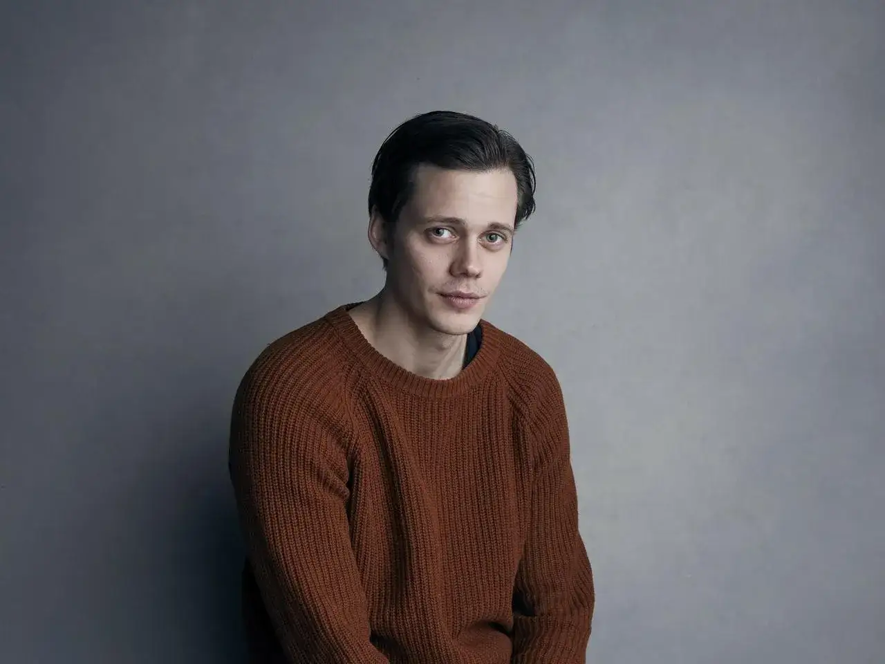 Bill Skarsgård w rudym swetrze, zastanawia się, w jakich filmach grał.