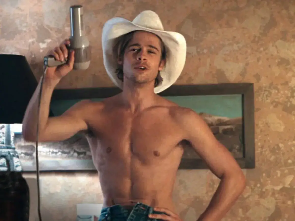 Brad Pitt w kowbojskim kapeluszu i bez koszulki, trzymający suszarkę. Wygląda jakby właśnie się dowiedział, kiedy urodził się Brad Pitt.