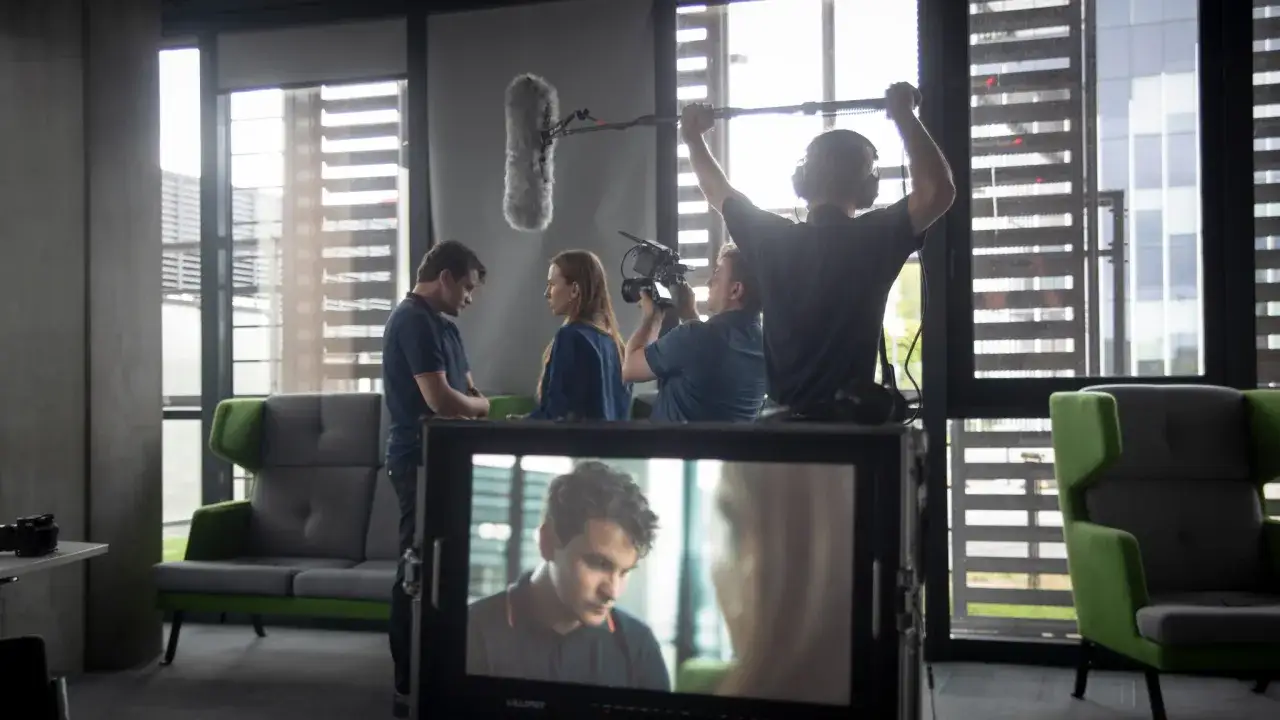 Scena filmowa, gdzie młoda kobieta uczy się, jak zostać aktorką, podczas nagrywania sceny z operatorem i dźwiękowcem.