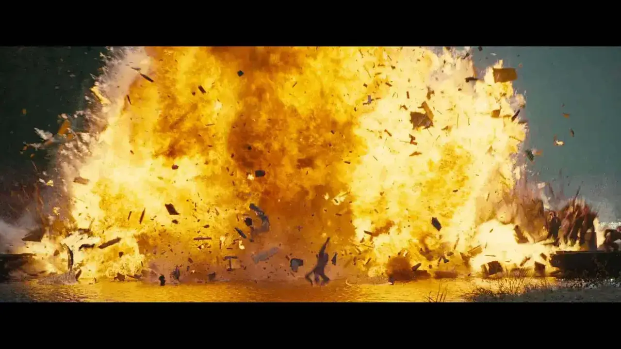 Potężna eksplozja w wodzie, jak w najlepszych filmach akcji ostatnich lat. Fragmenty latają w powietrzu, a w tle widać sylwetki ludzi.