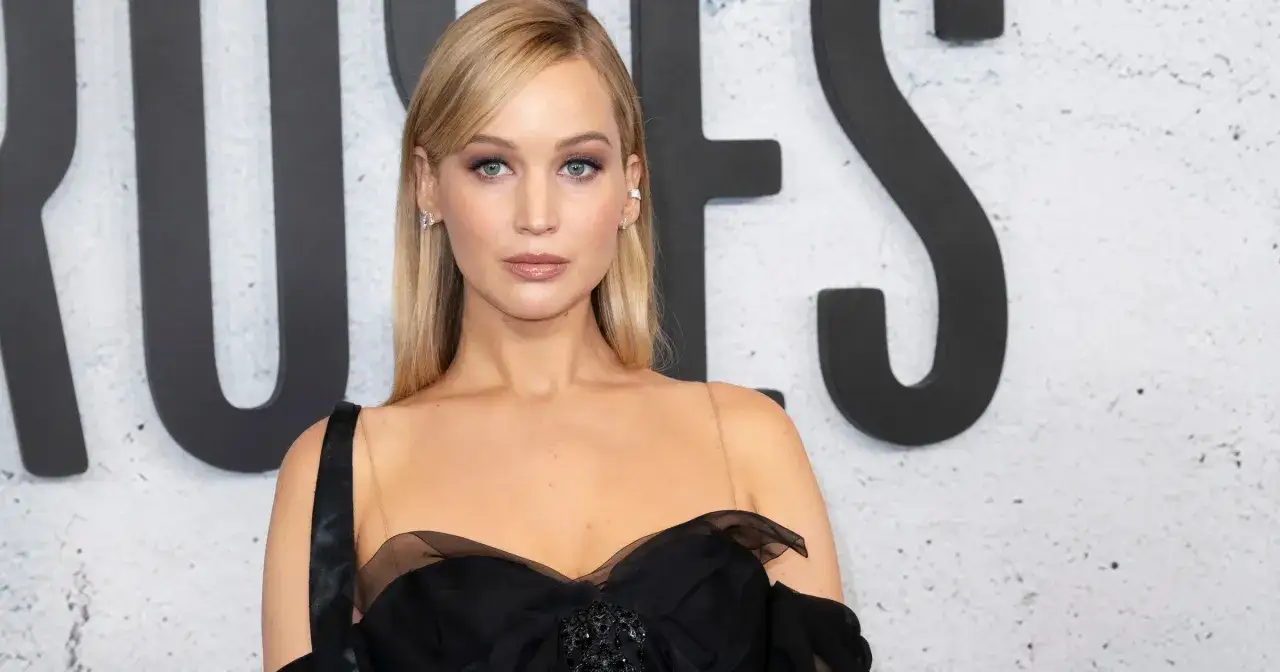Jennifer Lawrence w czarnej sukni z tiulowymi zdobieniami. Aktorka prezentuje się olśniewająco, a jej wiek, choć nie jest podany, wydaje się idealnie dopasowany do jej urody.