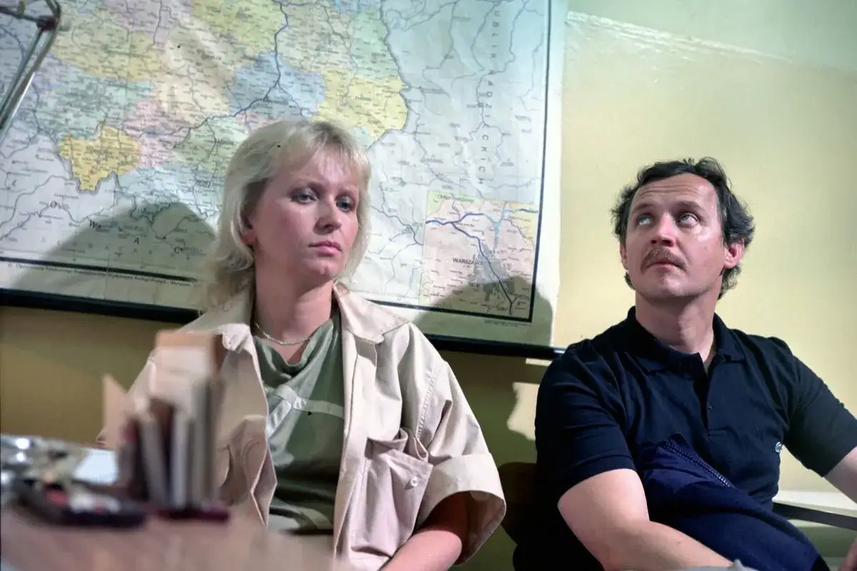 Para z mapą Polski w tle, jakby zagubieni w labiryncie filmowym.