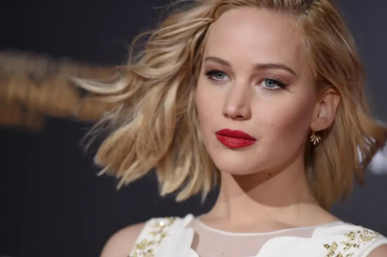 Jennifer Lawrence z burzą blond włosów i wyrazistą czerwoną szminką. Ile lat ma Jennifer Lawrence? W tym momencie ma 33 lata.